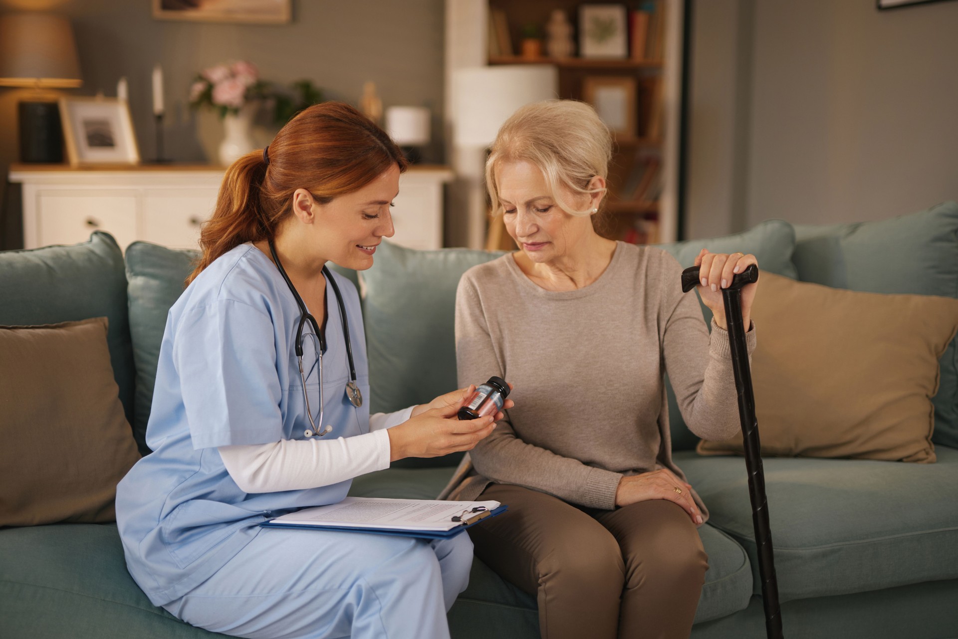Nurse showing medicine to senior woman at home visit